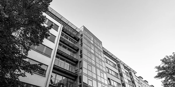 Die Aufnahme zeigt die Fassade eines modernen Hochhauses aus Glas, die hellblauem Himmel zugewandt ist, mit vielen Fenstern, die die Umgebung reflektieren.